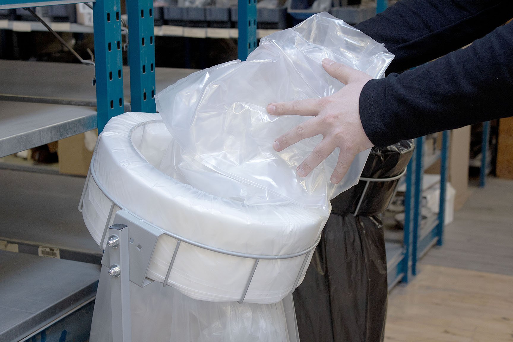 Mężczyzna wkłada plastik do worka na odpady w stojaku